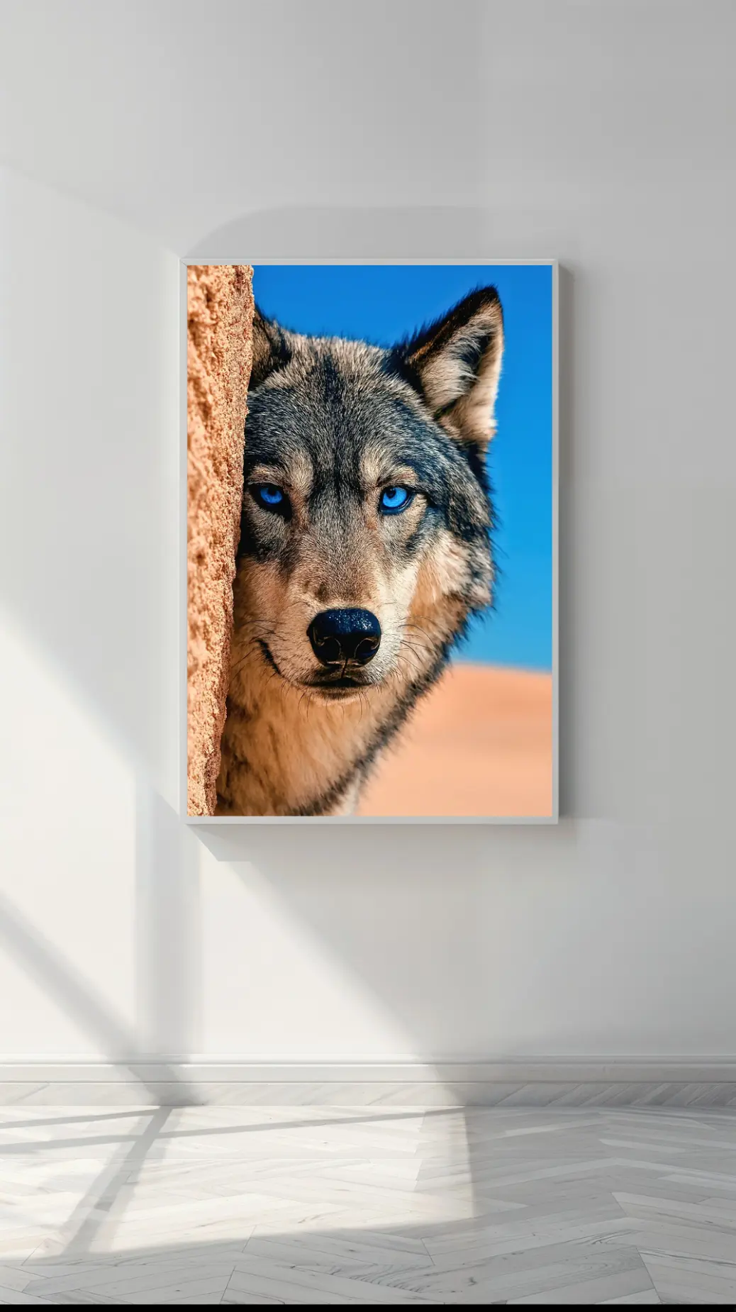 A stunning, high-resolution digital art print of a wolf with piercing blue eyes. The wolf&#39;s grey and brown fur contrasts with the bright blue sky and a warm, sandy rock it peeks from. This is a review image for an instant download printable, perfect for home decor.